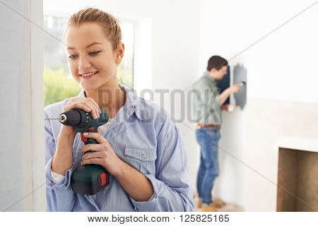 Young Couple Renovating Room In New Home Together