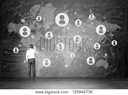 Businessman drawing network on grey concrete wall