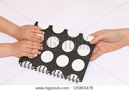 mother's hand pass black polka dots sealed spring notebook in hand Children