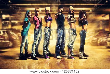 Dancer team pointing handsign to camera. Urban underground parking interior with light explosion effect.