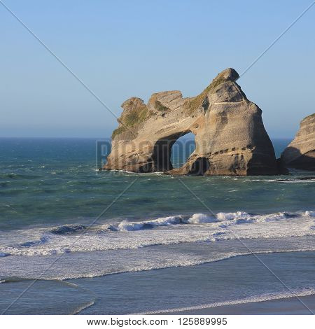 Island with a big hole at Wharariki Beach. Unique rock formation in New Zealand. Tourist attraction on the West Coast of the South Island.