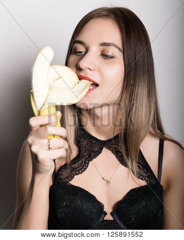 Young amazed woman in lacy lingerie holding a banana, she is going to eat a banana. she cleans Banana of a teeth.