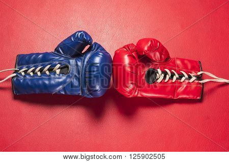 Boxing series : Blue and red boxing gloves on red leather background