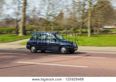 LONDON UK - 27TH MARCH 2015: A side view of a typical Black Cab in London during the day. A driver can be seen.
