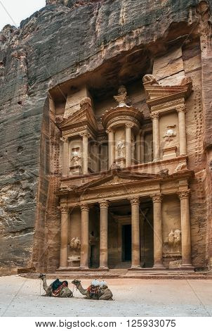 Two bedouin camels rests near the treasury Al Khazneh carved into the rock at Petra, Jordan. The city of Petra was lost for over 1000 years. Now one of the Seven Wonders of the Word