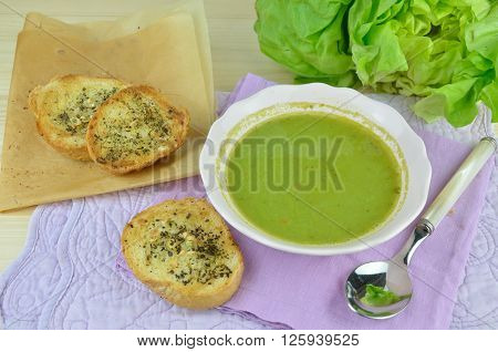 Bowl with fresh green cream soup (pottage) with garlic bread