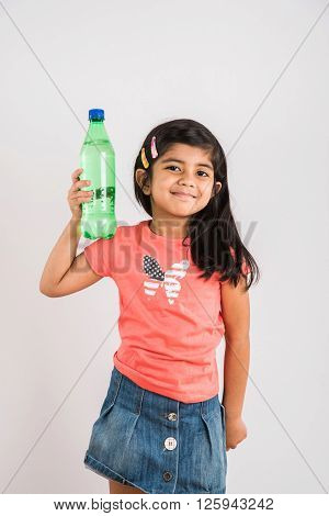 indian girl opening cold drink bottle, asian girl drinking cold drink in pet bottle, girl kid and cold drink, indian cute girl with lemon or carbonated cold drink in plastic bottle, isolated on blue