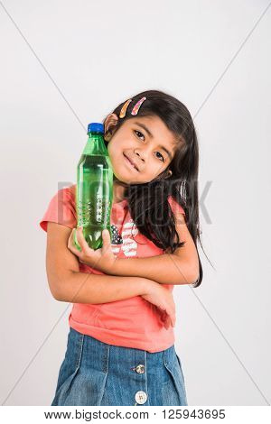 indian girl opening cold drink bottle, asian girl drinking cold drink in pet bottle, girl kid and cold drink, indian cute girl with lemon or carbonated cold drink in plastic bottle, isolated on blue