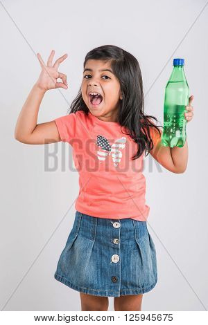 indian girl with cold drink bottle, asian girl drinking cold drink in pet bottle, girl kid and cold drink, indian cute girl with lemon or transparent juice in plastic bottle, isolated on white
