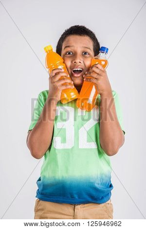 indian boy with cold drink bottle, asian boy holding cold drink bottle, small boy and cold drink, indian cute boy drinking mango juice or orange juice in plastic bottle