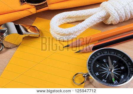 Orderliness White Scout Rope, Scarf, Whistle, Compass, Pencil And Paper Note On Wooden Table.
