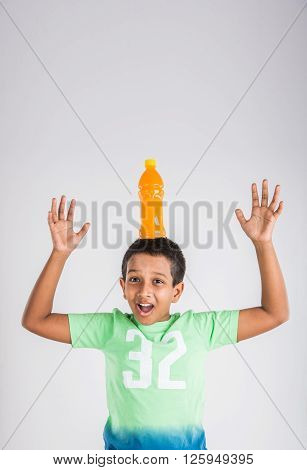 indian boy with cold drink bottle, asian boy holding cold drink bottle, small boy and cold drink, indian cute boy drinking mango juice or orange juice in plastic bottle