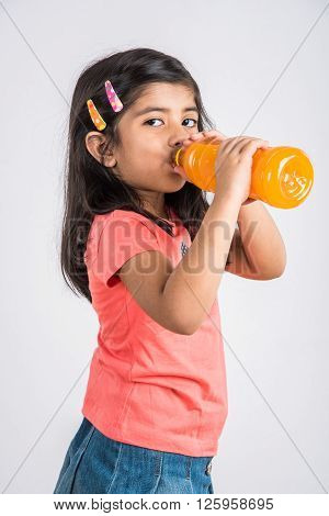 indian girl with cold drink bottle, asian girl drinking cold drink in pet bottle, girl kid and cold drink, indian cute girl with mango or orange cold drink in plastic bottle, isolated