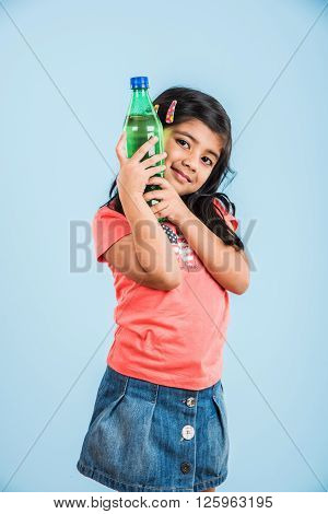 indian girl with cold drink bottle, asian girl drinking cold drink in pet bottle, girl kid and cold drink, indian cute girl with lemon or carbonated cold drink in plastic bottle, isolated on blue