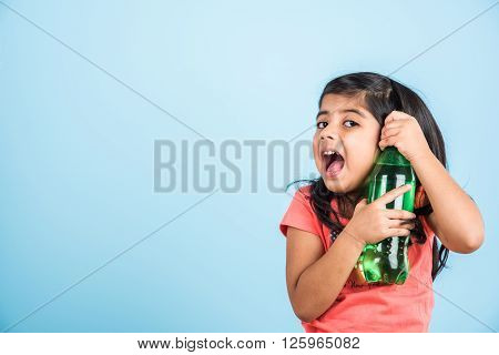indian girl with cold drink bottle, asian girl drinking cold drink in pet bottle, girl kid and cold drink, indian cute girl with lemon or carbonated cold drink in plastic bottle, isolated on blue