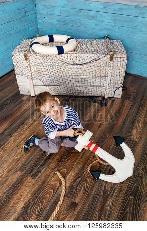 little boy sitting on the floor and holding the anchor looking at camera