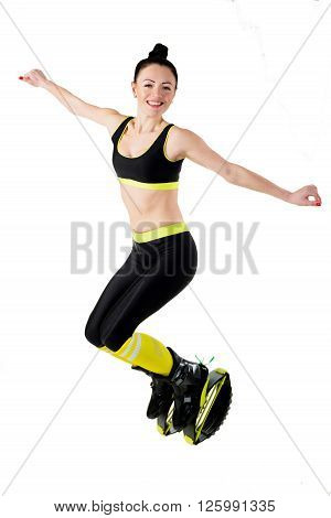 Smiling brunette girl in a black sportswear jumping in a kangoo jumps shoes. isolated on a white background.