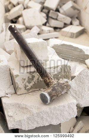Old steel hammer smashing on broken brick wall