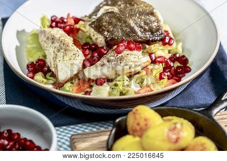 Skrei winter cod with skin fried on braised pointed cabbage with pomegranate seeds and roasted potatoes