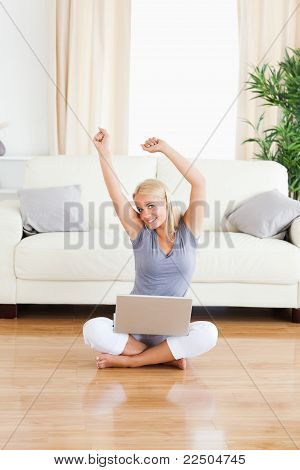 Portræt af en munter kvinde med en bærbare mens du sidder på Th