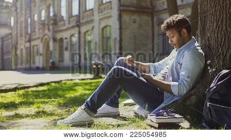 Surprised Guy Sitting Under Tree, Using Mobile Phone, Reacting To Newsfeed, Stock Footage
