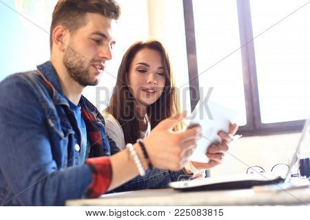 Teamwork concept.Young creative coworkers working with new startup project in modern office.Group of three people analyze data on desktop computer