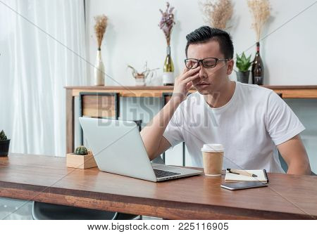 asia casual man cover face with hand upset from work in front of laptop computer in coffee shop,stress emotion concept,work outside office,work at home