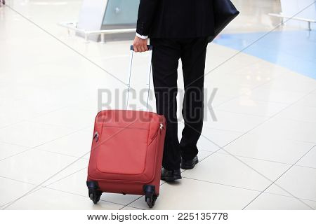 Business trip. Close-up of businessman carrying suitcase while walking through a passenger boarding bridge