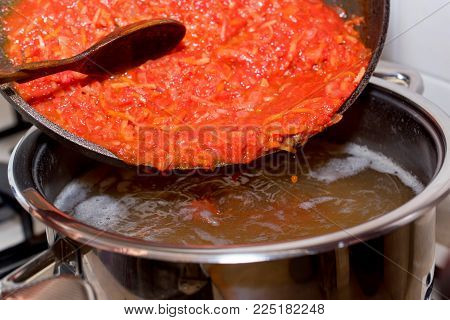 Close up adding roasted carrot and beet to borscht, vegetable soup