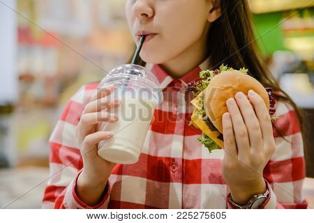 woman eat humburger and drink milk shake close up