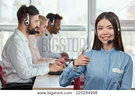 Asian girl praising colleagues. Japaneese girl shows her approval, thumb up.