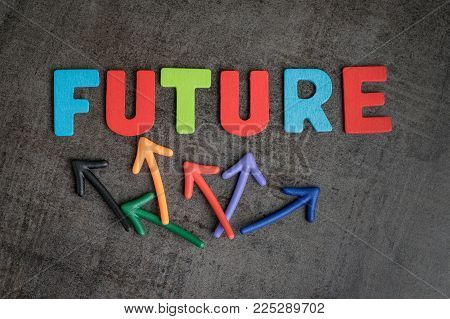 Uncertain future or next business goal concept, colorful wooden alphabets arrage word FUTURE with multi directional arrow on dark black chalckboard wall, risk or fear for life journey.