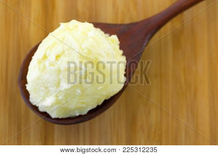 Cold pressed unrefined Shea butter fat extracted from nut seed of African Shea tree in wooden spoon (Vitellaria paradoxa)