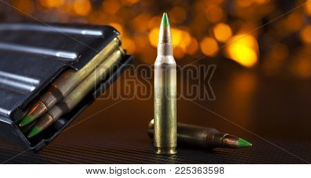 M855 Ammunition And Metal Magazine For Ar-15s With An Orange Background