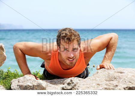 Fit man doing push-ups in summer beach outdoor. Athlete training muscles doing push up exercises outdoors. Healthy lifestyle concept. Fitness lifestyle.