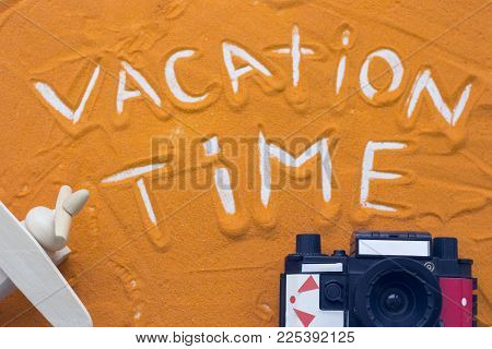 Vacation Time Inscription On An Orange Colored Sand With Roll Film Camera And Wooden Toy Plane, Top 