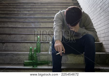 Depressed Man Sit In Underground Road With Beer And Cigarette