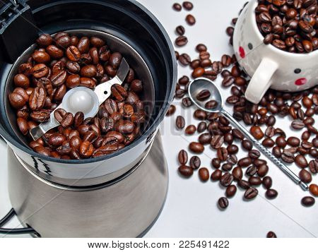 Electric Coffee Grinder With Roasted Coffee Beans Inside And Coffee Beans Scattered On A Table With 