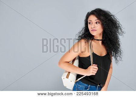 Sexy Young Girl With Black Curly Hair Carrying White Backpack With A Golden Zipper. She Wears Black 