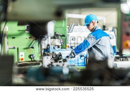 Cnc Metal Lathe Technician Worker. Caucasian Contractor Operating Heavy Duty Metalworking Machinery.