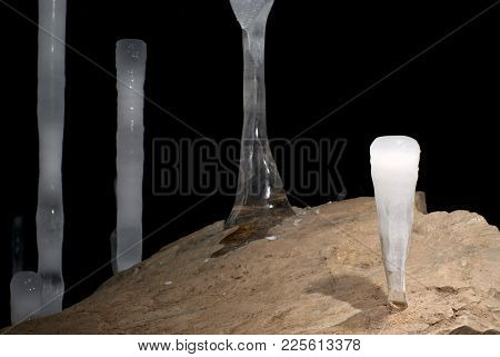 Ice Stalagmites On A Stone Boulder In A Cave On A Dark Background Closeup