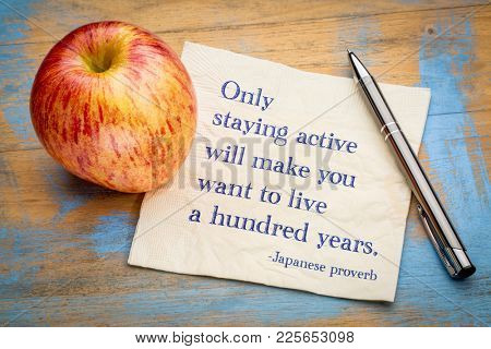 Only staying active will make you want to live a hundred years, Japanese proverb - handwriting on a napkin with a fresh apple