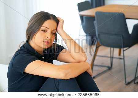 A Lonely Young Woman Sitting On The Couch At Home, She Is Depressed And Separated From Problems In H