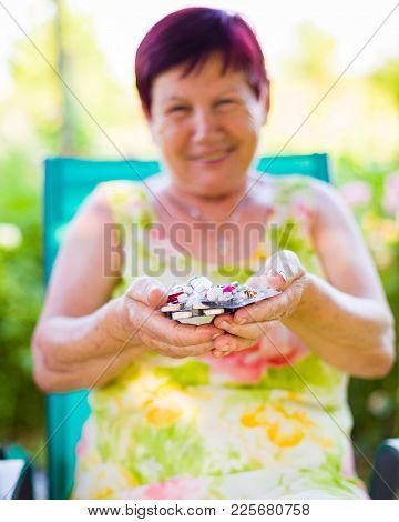 Closeup Of Elderly Woman Holding Her Expensive Drugs And Being Smiling Outdoors.