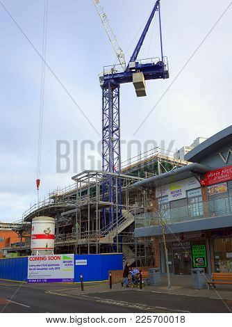 Bracknell, England - February 08, 2018: A Woman Pushing A Pram Passes By A Parade Of Retail Shops An