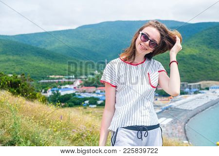 Teen Girl 17s Stands On The Hill In Sun Glasses Looking At The Camera. In The Background The Sea, Ci