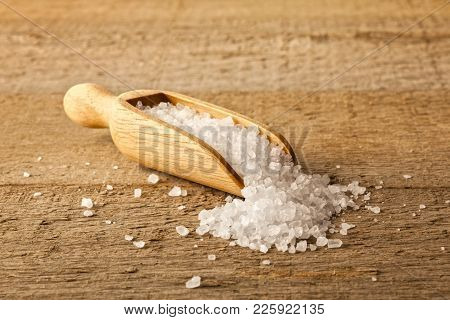 Salt Crystals In A Scoop - A Small Wooden Scoop Filled With Salt Crystals Which Are Spilling Onto A 