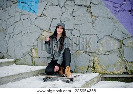 Stylish Brunette Girl In Gray Cap, Casual Street Style With Skate Board On Winter Day Against Colore
