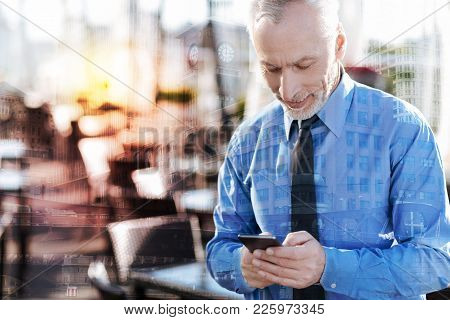 Quick Messages. Calm Concentrated Mature Businessman Standing Alone In A Nice Cafe And Feeling Satis