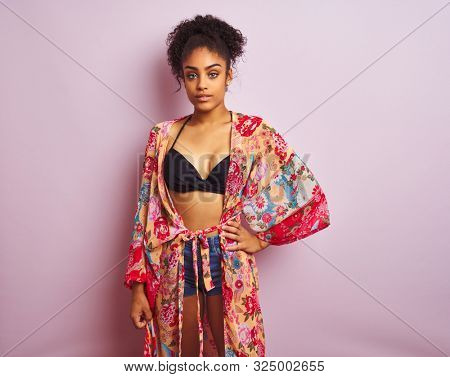 Young beautiful african american woman on vacation standing wearing bikini and colorful caftan